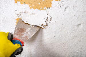 Hand scraping flaking paint down to sound paint on a historic exterior wall