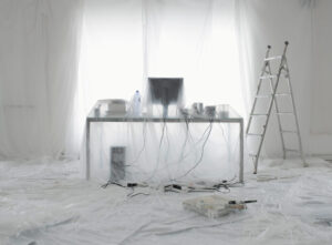 Interior room sealed with plastic sheeting and drop cloths before painting work begins