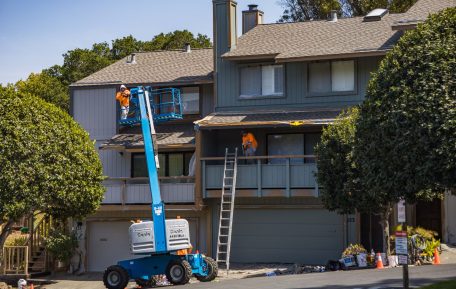 Painters on a lift renovating a home exterior
