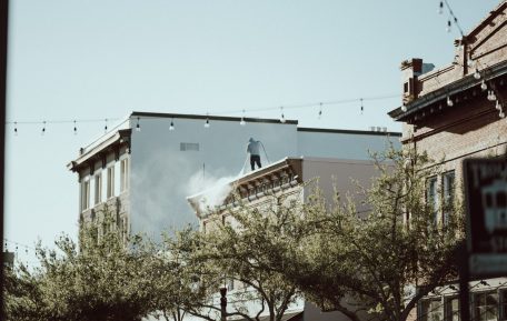 Worker pressure washing a building before painting