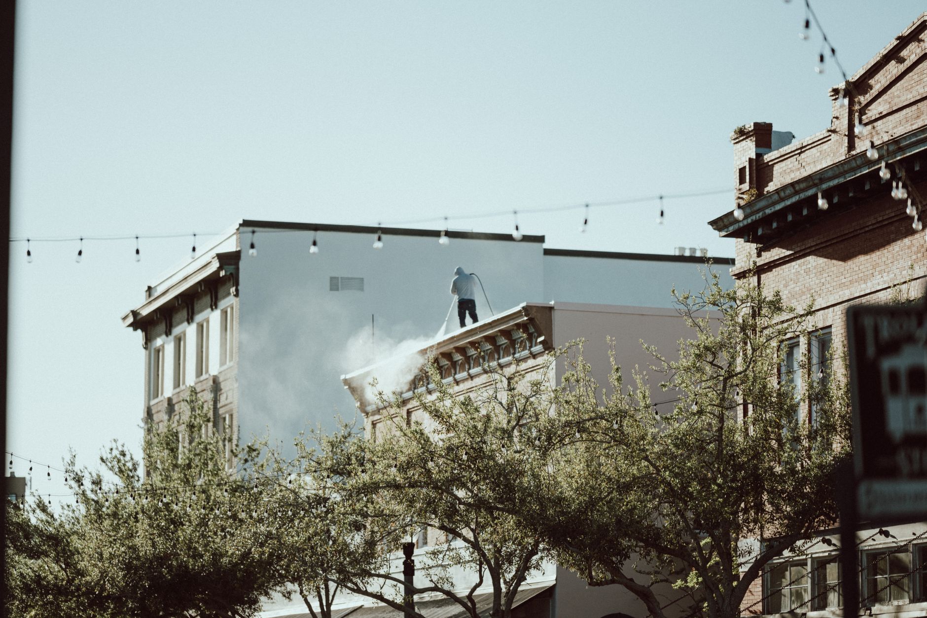 Worker pressure washing a building before painting